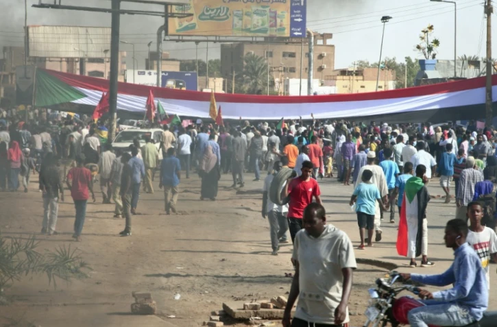 Des manifestants ont dressé un gigantesque drapeau soudanais lors d'une manifestation à Omdourman, la ville jumelle de Khartoum, pour réclamer le retour du pouvoir civil au Soudan, le 13 décembre 2021
