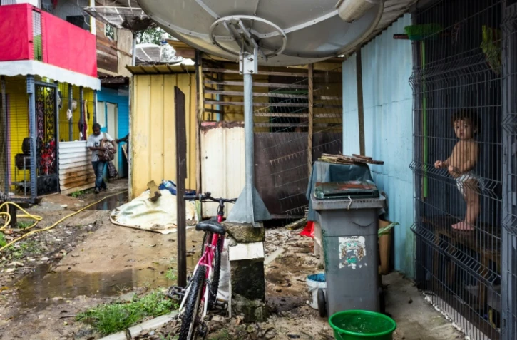 Un bébé debout derrière un grillage dans le bidonville "la Matine" à Cayenne le 6 avril 2017