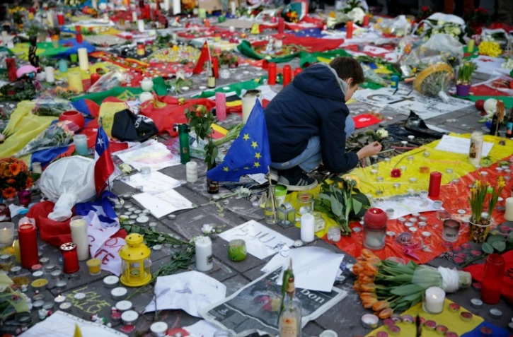 Un garçon allume une bougie en hommage aux victimes des attentats de Bruxelles, Place de la Bourse, le 23 mars 2016