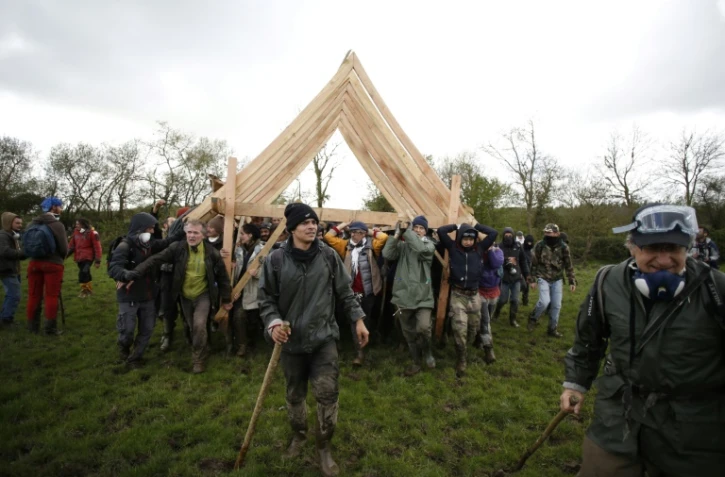 Des occupants de la ZAD portent une charpente pour reconstruire l'un des squats, le 15 avril 2018 Ă Notre-Dame-des-Landes