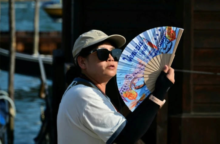 Une touriste utilise un éventail pour se rafraîchir, place Saint-Marc, à Venise, lors d'un épisode de canicule en Europe, le 26 juin 2026