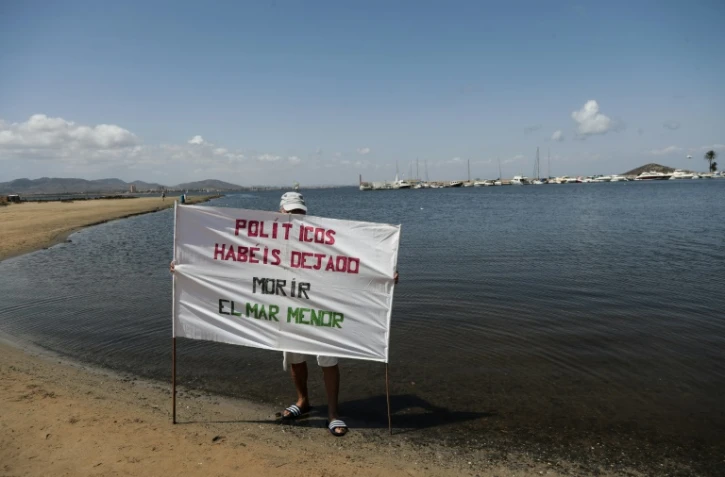 Un militant tient une bannière sur laquelle est écrit "Politiciens, vous avez laissé mourir la mer Mineure", le 25 août 2021 à Puerto Bello de la Manga, en Espagne