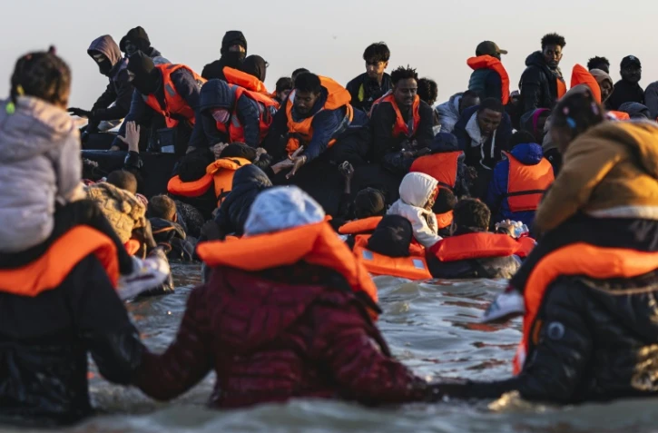 Des migrants montent à bord d'un bateau de passeurs pour traverser la Manche, au large de la plage de Gravelines, le 16 juin 2025 dans le Nord