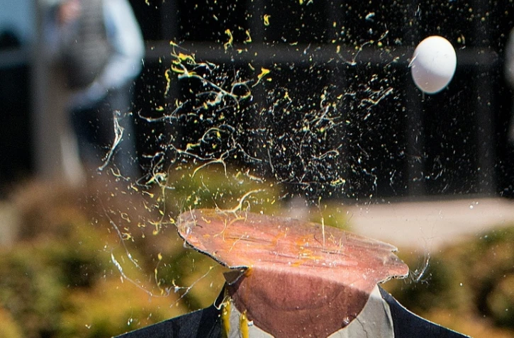 Jet d'oeuf sur une pancarte à l'effigie de Donald Trump lors d'une manifestation en marge d'un discours du candidat aux primaires présidentielles, à Burlingame en Californie le 29 avril 2016  