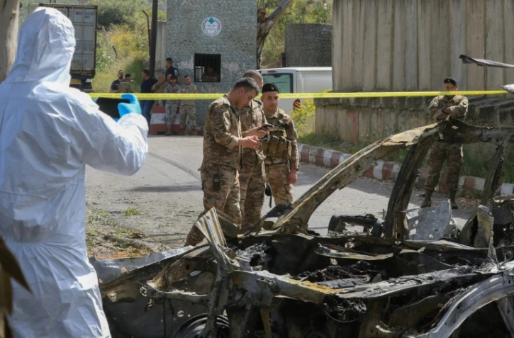 Des membres des forces de sécurité libanaises et des experts médico-légaux inspectent une voiture détruite par une frappe aérienne israélienne, près de la ville côtière de Damour, au sud de Beyrouth, le 22 avril 2025