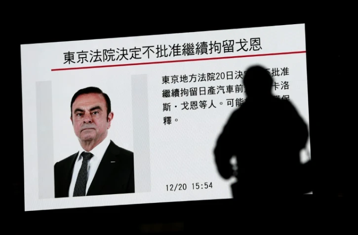 Un piéton passe devant un écran sur lequel est diffusé un programme sur l'ex PDG de Renault et de l'Alliance Renault-Nissan Carlos Ghosn, à Tokyo, le 20 décembre 2018