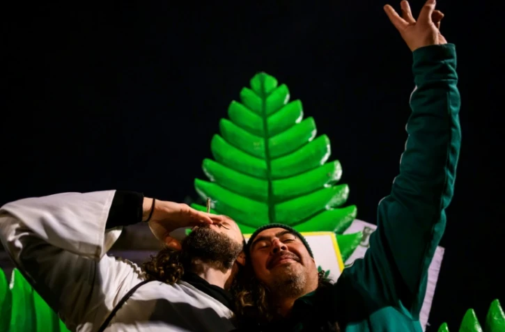 Des fumeurs de marijuana célèbrent la légalisation du cannabis récréatif en Allemagne, le 1er avril 2024 devant la porte de Brandebourg à Berlin