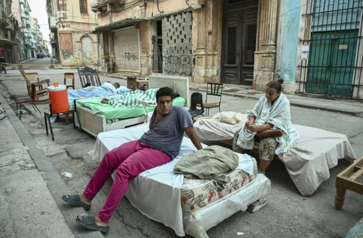 Plusieurs familles passent la nuit sur des lits installés dans la rue, dans un quartier central de La Havane, le 30 juillet 2026, après l'effondrement partiel de leur immeuble