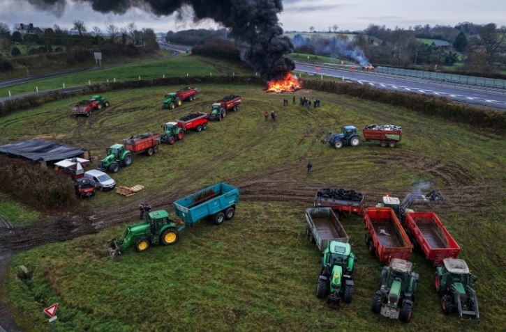 Des agriculteurs allument un feu alors qu'ils participent, avec leurs véhicules, à un blocage d'autoroute, à Poilley, dans l'ouest de la France, le 5 janvier 2026