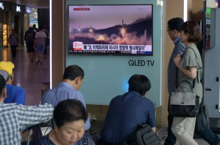 Des personnes passent devant un écran de télévision montrant des images d'archives d'un lancement de missile par la Corée du Nord à Séoul le 26 août 2017