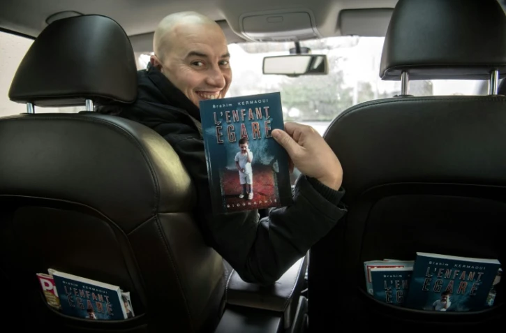 Chauffeur VTC et écrivain, Brahim Kermaoui pose avec son livre "l'Enfant égaré" à Asnières-sur-Seine, au nord-ouest de Paris, le 13 décembre 2017