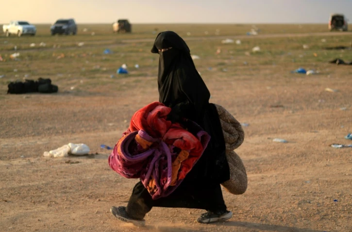 Une femme portant des couvertures est photographiée après avoir fui le dernier bastion du groupe Etat islamique (EI) dans l'est de la Syrie, le 22 février 2019