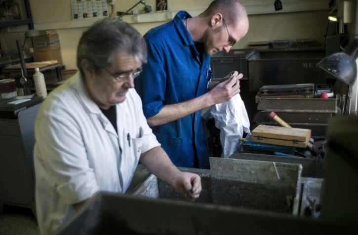 Un jeune homme, alors employé avec un contrat de génération, travaille aux côtés d'un employé plus âgé, le 25 mars 2013 dans un atelier d'assemblage d'optique à Mitry-Mory, en Seine-et-Marne