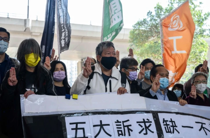 (g-d) Les militants prodémocratie Leung Kwok-hung, alias "Long Hair", Lee Cheuk-yan, Albert Ho et Cyd Ho font le salut à trois doigts à leur arrivée au tribunal de West Kowloon, le 16 février 2021 à Hong Kong