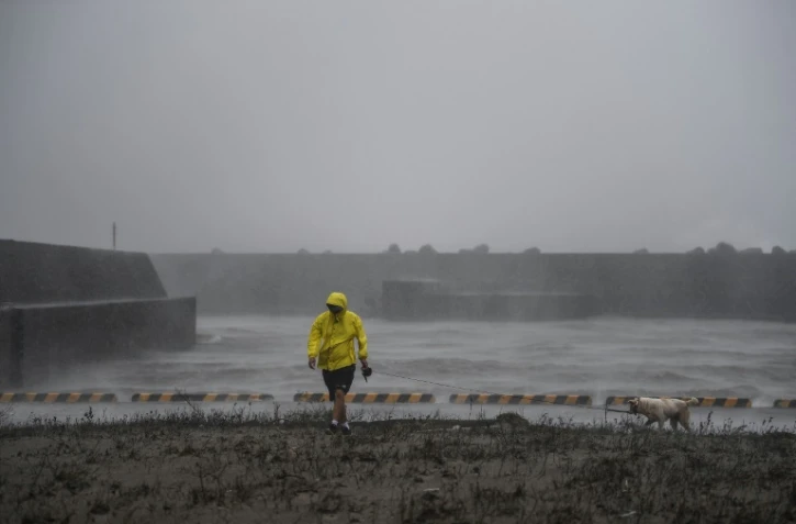 Un homme marche avec son chien à Ichikikushikino (Japon) le 7 septembre 2020 après le passage du typhon Haishen 
