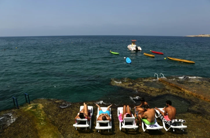 Des Libanais prennent un bain de soleil au bord de la mer à Anfeh, au nord de Beyrouth, le 23 août 2016