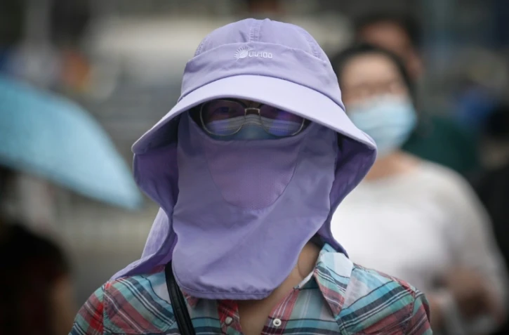 Une femme portant un masque et un capuchon pour se protéger du coronavirus, dans une rue de Pékin le 23 juin 2020