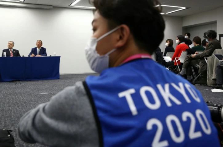 Un photographe portant le gilet des JO de Tokyo 2020lors d'une conférence de presse sur le report de cet événement sportif, à Tokyo le 24 mars 2020