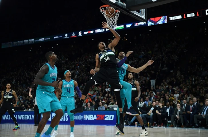 La star des Milwaukee Bucks Giannis Antetokounmpo (C) claque un dunk malgré trois joueurs des Charlotte Hornets en défense, le 24 janvier 2020 à Paris