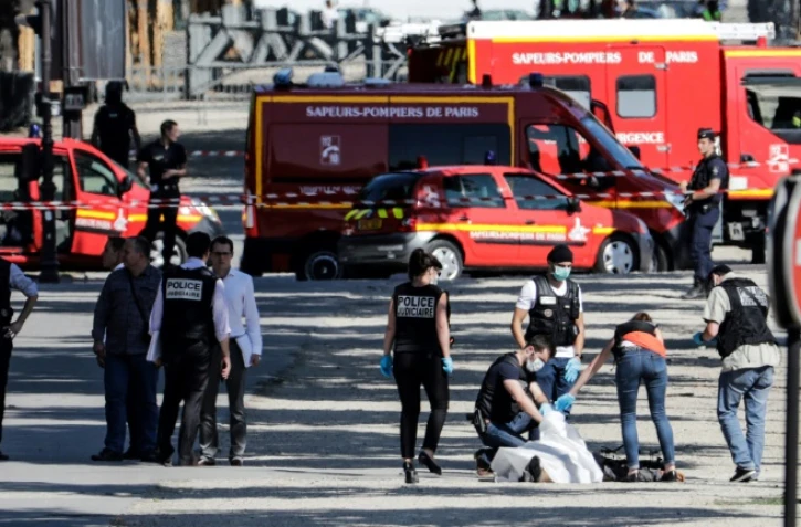 Des membres de la police judiciaire enveloppent le corps de l'auteur de l'attentat raté sur les Champs-Elysées à Paris, le 19 juin 2017