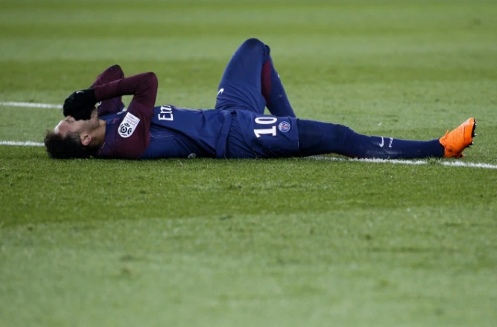 La star du PSG Neymar au sol après s'être blessé à la cheville droite contre Marseille en Ligue 1, le 25 février 2018 au Parc des Princes