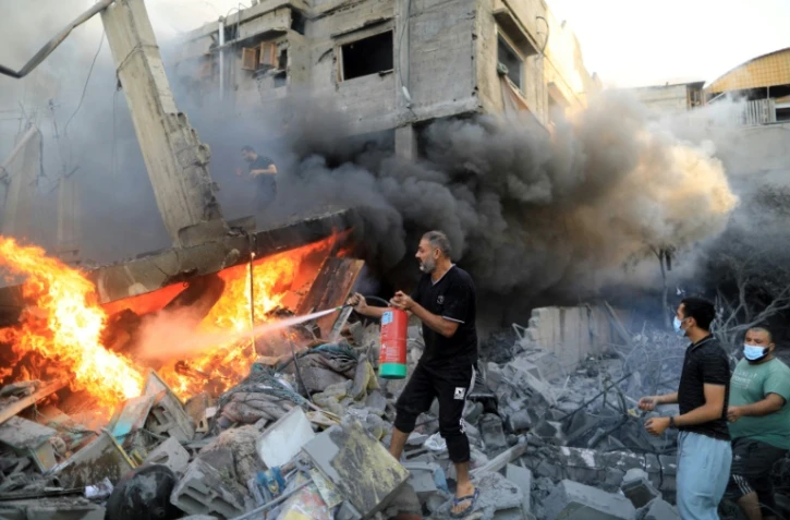 Un Palestiniens tente d'éteindre un incendie après une frappe israélienne qui a détruit une habitation à Khan Younès dans le sud de la bande de Gaza, le 14 octobre 2023