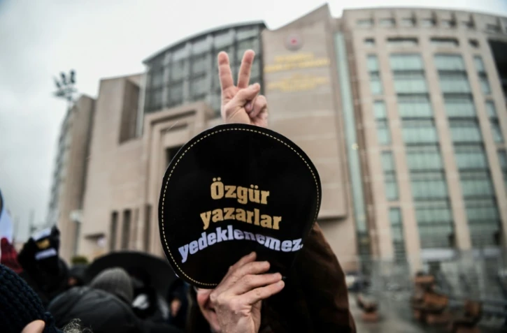 Un homme brandit un écusson "Ecrivains votre liberté n'est pas assurée" le 29 décembre 2016 devant le tribunal où se déroule le procès de la romancière Asli Erdogan
