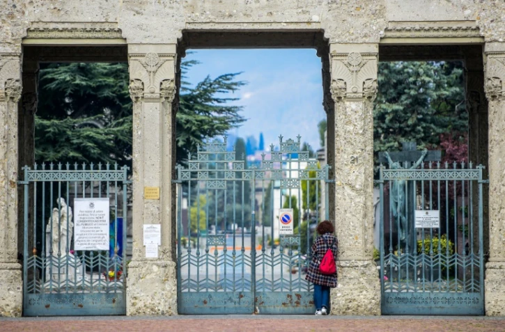 Une femme devant les grilles du cimetière de Bergame (Italie), fermé au public, le 20 mars 2020