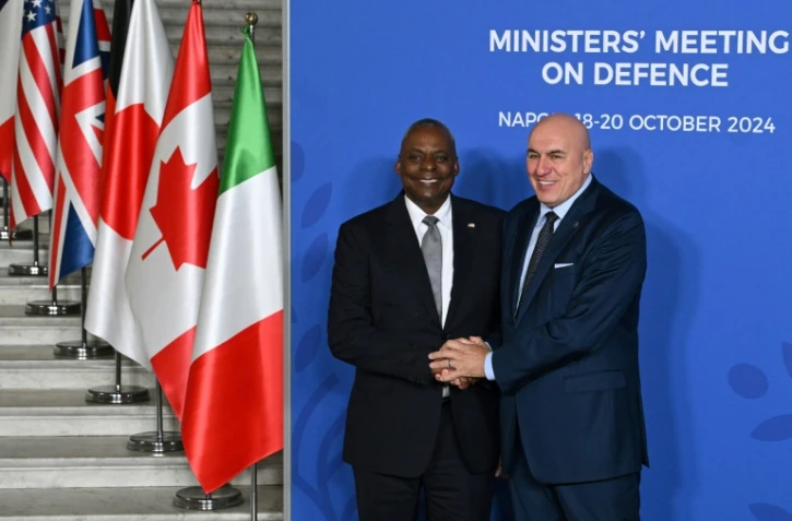 Le ministre italien de la Défense Guido Crosetto (D) et son homologue américain Lloyd Austin se serrent la main pendant la cérémonie d'accueil d'un G7 Défense à Naples, en Italie, le 19 octobre 2024
