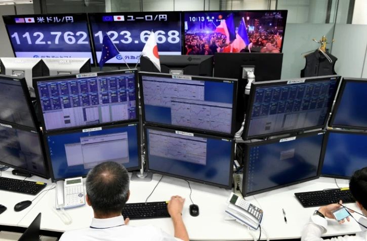 Des courtiers suivent à la télévision la retransmission de l'élection d'Emmanuel Macron à la présidence de la République à la Bourse de Tokyo, le 8 mai 2017