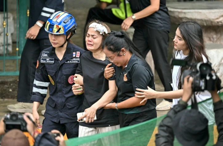 L'épouse (C) d'un professeur tué par un adolescent dans un lycée au nord de Bangkok est emmenée vers une ambulance, dans le district de Bang Kruai, en Thaïlande, le 7 août 2026