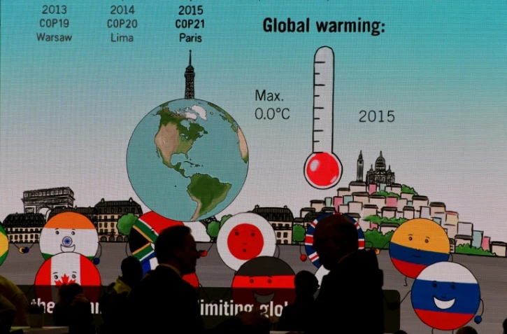 Des visiteurs passent devant un écran géant durant la Cop 23 à Bonn (Allemagne) le 8 novembre 2017