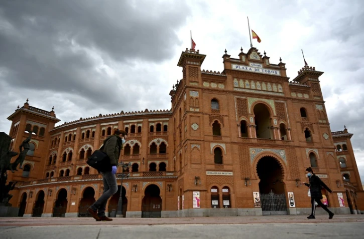 Des passants portant un masque de protection dans une rue de Madrid pendant le confinement instauré pour lutter contre l'épidémie de coronavirus, le 22 avril 2020 en Espagne