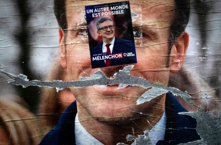 Une affiche électorale pour le candidat de la gauche radicale Jean-Luc Mélenchon apposée sur une autre affiche pour Emmanuel Macron, le 19 avril 2022 à Paris