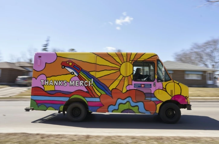 L'un des 37 camions de livraison de la Poste canadienne, repeint de couleurs vives pour apporter un peu de lumière dans la grisaille de la pandémie, circule le 12 mars 2021 à London (Ontario)