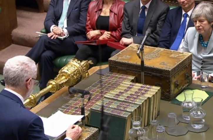 Capture écran d'une vidéo du Parlement britannique montrant Theresa May (d) écouter Jeremy Corbyn, à la Chambre des communes, le 25 mars 2019