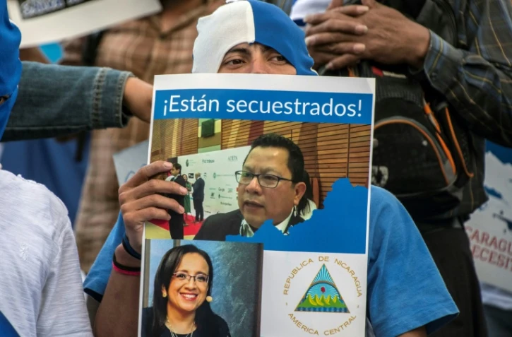 Un Nicaraguayen brandit une pancarte de soutien aux journalistes Miguel Mora et Lucia Pineda, accusés de terrorisme par le régime de Daniel Ortega, lors d'une manifestation le 22 décembre 2018 à San José au Costa Rica