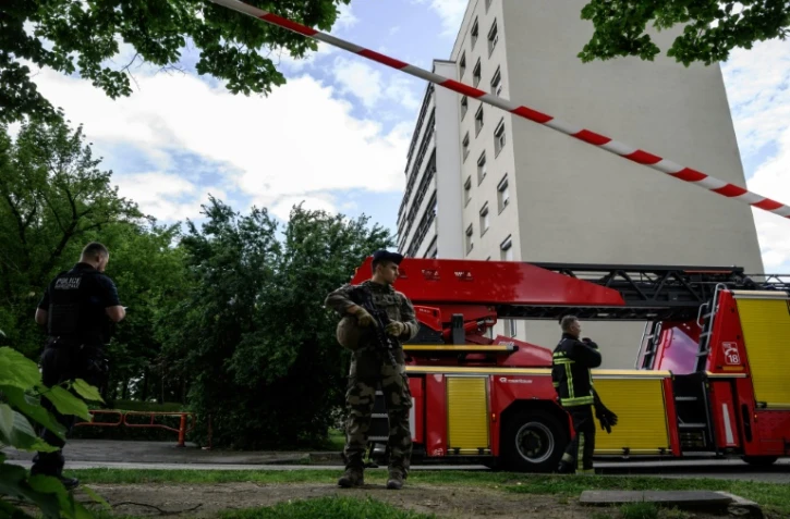 Un membre de l'opération Sentinelle monte la garde aux côtés d'un policier et d'un pompier sur le site d'un incendie qui s'est déclaré dans un immeuble résidentiel à Décines-Charpieu, en périphérie de Lyon, le 11 mai 2026