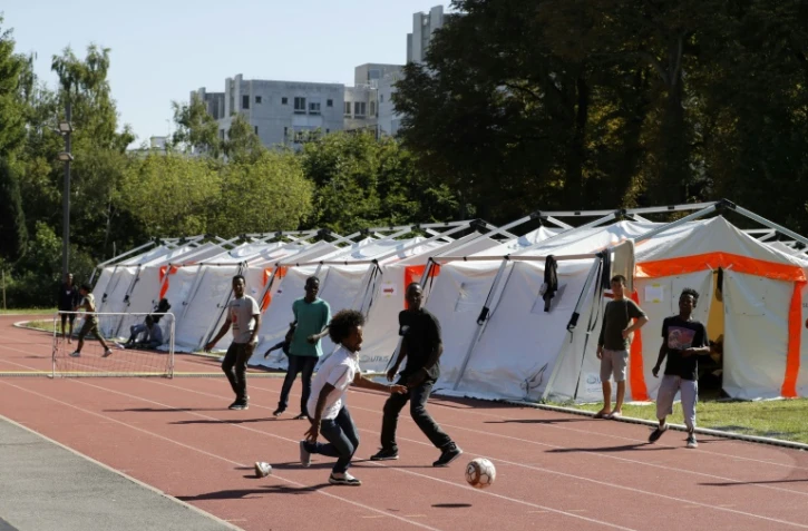 Des migrants jouent au foot devant des tentes installées par la Sécurité civile sur un terrain de sport dépendant de l'Université Panthéon-Assas le 22 août 2017 