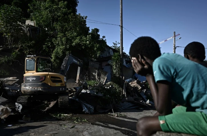Des habitants assistent à la démolition des cases en tôle du bidonville Talus 2, le 22 mai 2023 à Mayotte