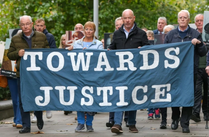 Des proches des victimes du "Bloody Sunday" brandissent une banderole sur laquelle est écrit "Towards Justice" (En faveur de la justice) alors qu'ils se rendent à pied au tribunal de Belfast, en Irlande du Nord, le 16 octobre 2025