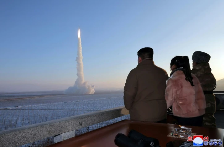 Photo diffusée par KCNA le 19 décembre 2021 du dirigeant nord-coréen Kim Jong Un (G) et de sa fille qui assistent au tir d'un missile Hwasong-18 de classe ICBM