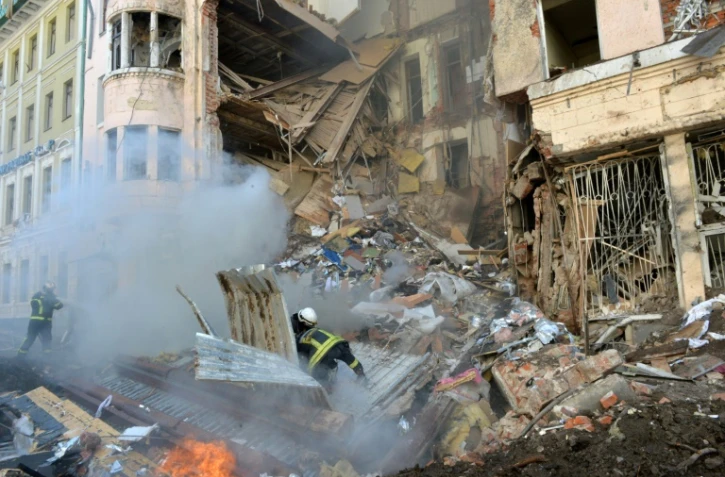 Des pompiers s'affairent auprès d'un immeuble éventré par une frappe russe à Kharkiv, dans l'est de l'Ukraine, le 14 mars 2022