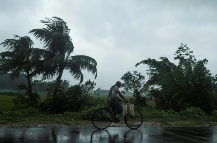 Un homme à vélo sous la pluie, avant l'arrivée du cyclone Amphan, le 20 mai 2020 à Midhapore, en Inde