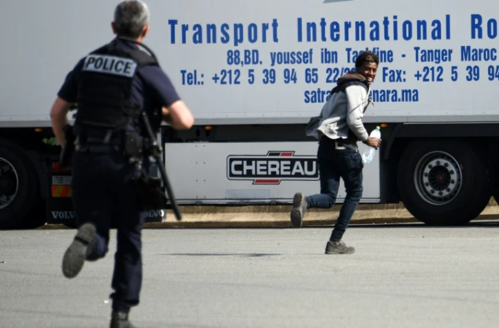 Un policier poursuit un jeune homme suspecté d'être un migrant, dans les environs de Calais le 5 juillet 2017