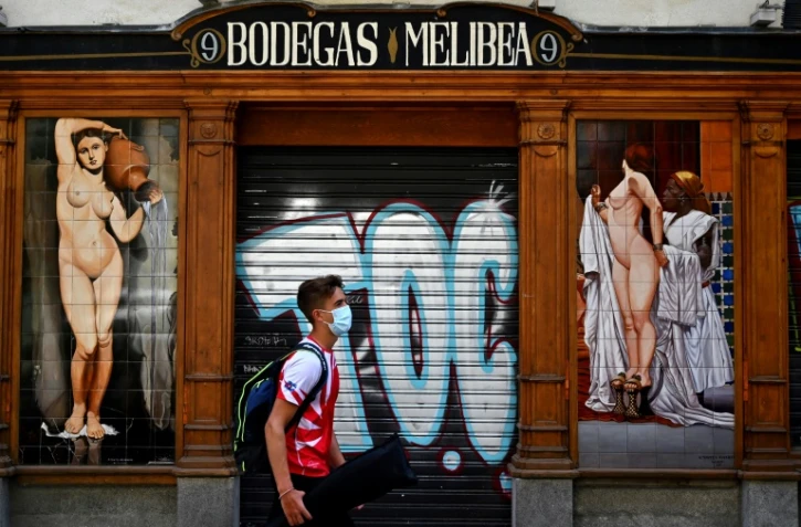 Un jeune homme passe devant un bar fermé à Madrid, en Espagne, le 9 juillet 2020