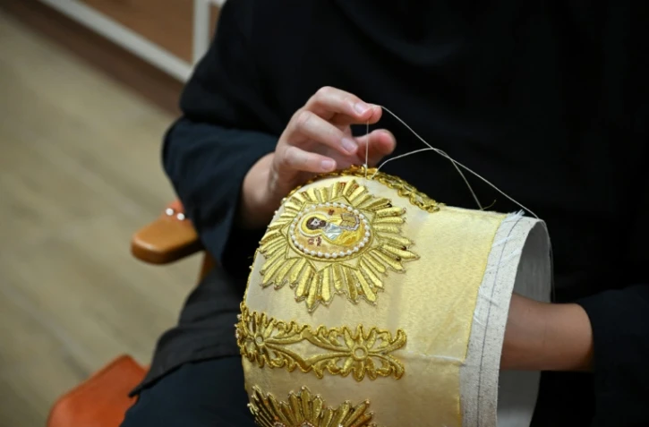La religieuse chrétienne orthodoxe sœur Élisabeth brode au fil doré des motifs et détails sur une mitre, au monastère de Saint-Georges le Victorieux à Rajcica, le 18 juin 2025 en Macédoine du Nord
