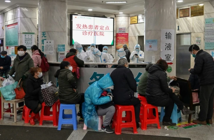 Du personnel médical en combinaison de protection reçoit des patients à l'hôpital de la Croix-Rouge à Wuhan, le 24 janvier 2020 en Chine
