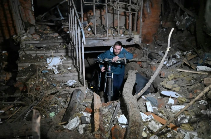 Un habitant de Kharkiv retire un vélo d'un immeuble endommagé par une frappe russe, le 30 décembre 2023