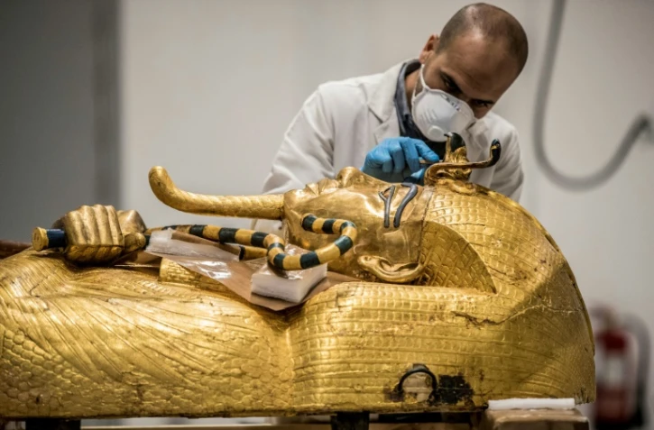 Un archéologue effectue des restaurations sur le sarcophage en or de l'ancien pharaon égyptien Toutânkhamon au laboratoire de restauration du Grand Musée égyptien (GEM) à Gizeh, dans la banlieue sud-ouest du Caire, le 13 avril 2020 en Egypte